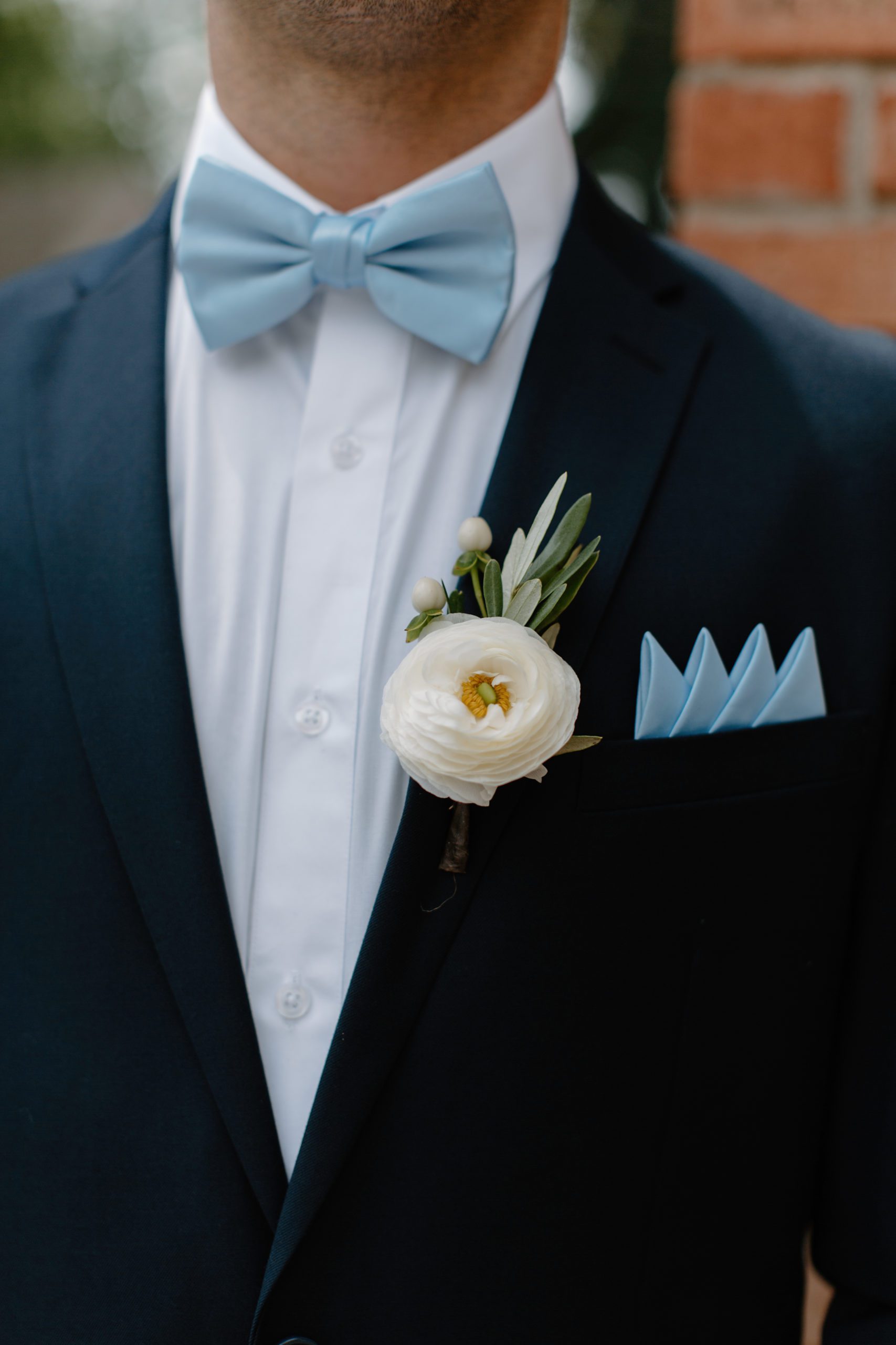 close up of man in blue suit with ivory flower on lapel